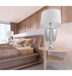 La lampada da tavolo o comodino OLIMPIA con paralume bianco un mix di tre materiali vetro argentato, metallo e tessuto ignifugo.